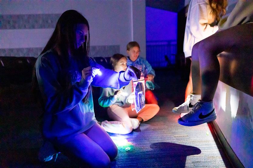 Students use hand lights in the theater